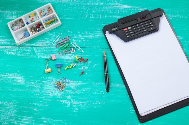 A calculator next to a notepad and pen, representing the process of calculating an emergency fund. The backdrop is a clean desk with organized papers.