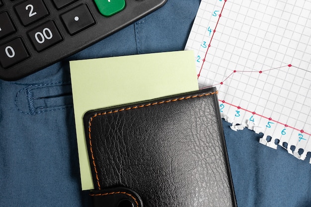 A close-up view of a credit card with a calculator and a pen lying next to it. The background includes financial charts and graphs.