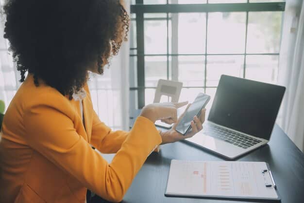 A person on the phone while filling out an online form on their laptop. This conveys that the person is trying to apply for an extension of their unemployment benefits.