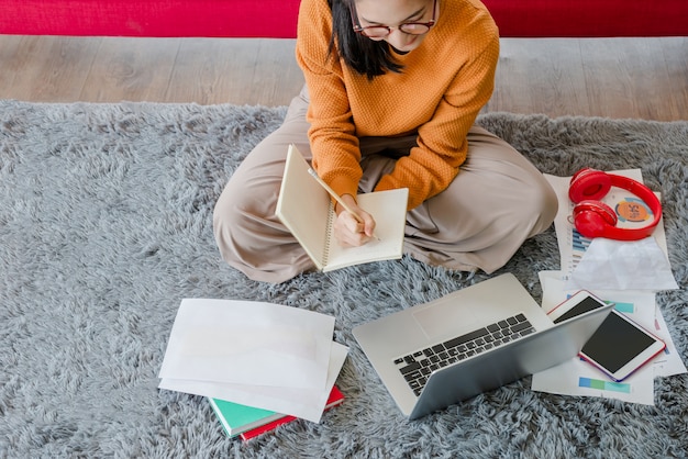 A person studying online with a laptop, surrounded by books and notes, indicating continuous learning and upskilling. The environment is a cozy home office.