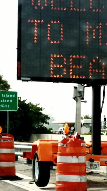 A digital display board on a highway showing an emergency alert message about traffic delays due to an accident, illustrating real-time information dissemination.
