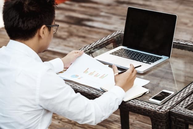 A person working on a laptop, reviewing financial data and preparing a business plan for the grant application.