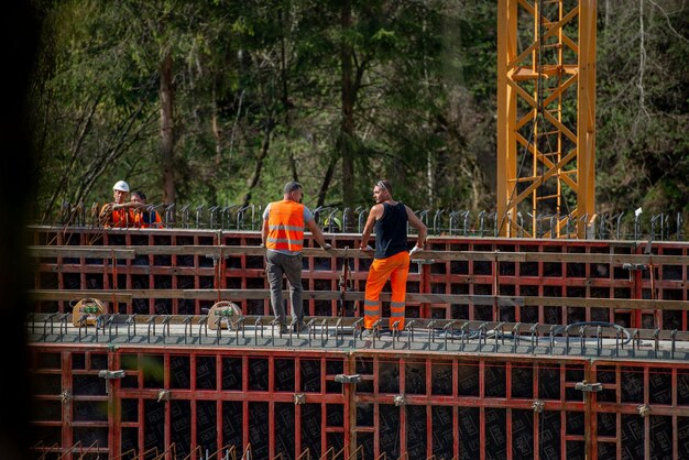 A construction site with workers and heavy machinery building a new bridge, emphasizing safety measures and the scale of the project.